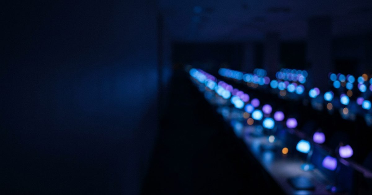 Rows of desk lights glowing blue and violet on a call center floor at night