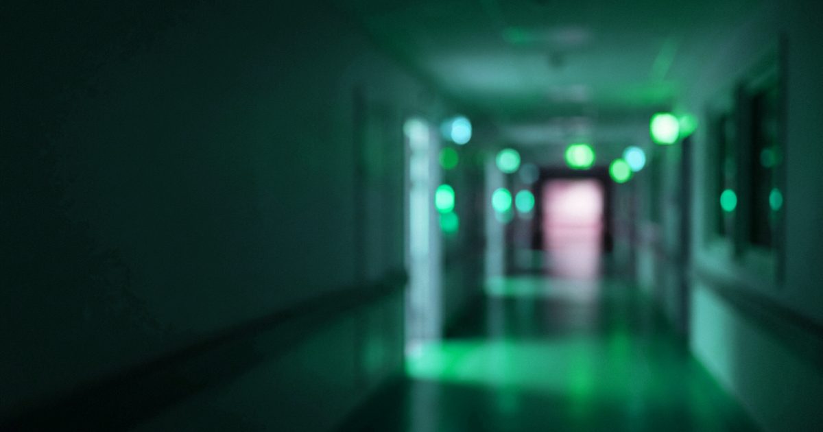 A quiet hospital corridor at night in soft blue and violet light