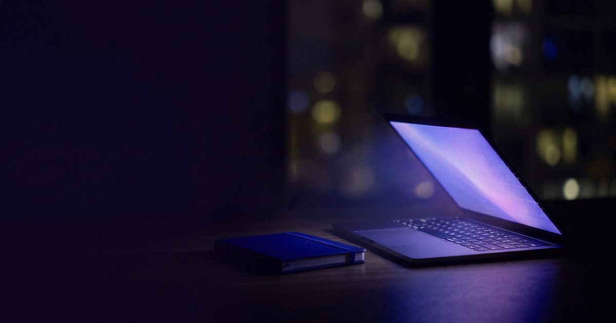 A laptop half open on a minimal desk casting blue light
